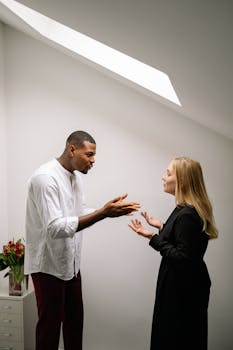 A serious discussion between two colleagues in an office setting, highlighting workplace conflict.