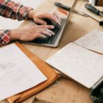 A woodworker uses a laptop to design furniture in a workshop setting, highlighting the blend of technology and craftsmanship.
