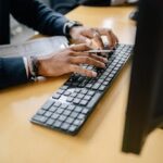 Close-up of hands typing on keyboard in an office setting, showcasing work professionalism.