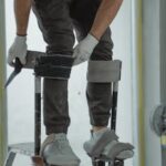 Construction worker on stilts in a house renovation project, using tools.