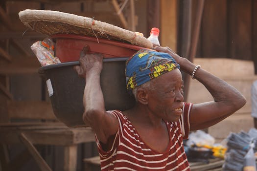 Elderly woman at an outdoor market carrying goods, showcasing small business operations.