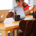 Group working in a cozy cafe with laptops and coffee mugs on a shared table.