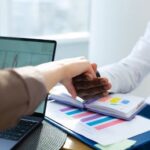 Office colleagues engaging in a handshake during a productive meeting, showcasing teamwork and collaboration.