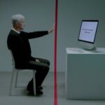 Senior man facing age discrimination in workplace, seated opposite a computer.