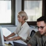 Two professionals working intently at desks in a contemporary office environment.