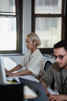 Two professionals working intently at desks in a contemporary office environment.