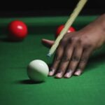 A close-up shot of a billiard player aiming at the balls on a green table. Perfect for sports themes.