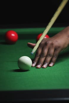 A close-up shot of a billiard player aiming at the balls on a green table. Perfect for sports themes.