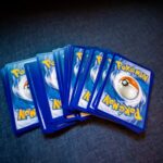 A collection of Pokemon trading cards laid out on a dark surface, showcasing their distinct back designs.