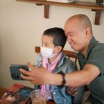A father and son capture a selfie in a cozy indoor setting, sharing a joyful moment.