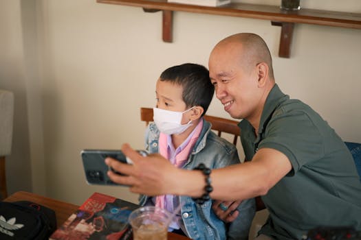 A father and son capture a selfie in a cozy indoor setting, sharing a joyful moment.