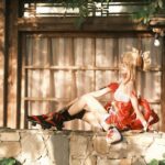 A woman in detailed cosplay attire sits elegantly outdoors in warm sunlight.