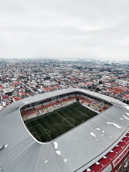 Aerial shot of a modern football stadium amidst a sprawling urban cityscape during winter.