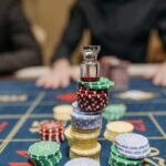 Close-up of colorful casino chips stacked on a roulette table in a casino setting.