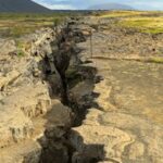 Explore the rugged terrain of a dramatic geological rift on an island under a moody sky.