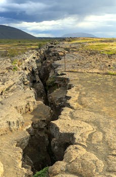 Explore the rugged terrain of a dramatic geological rift on an island under a moody sky.