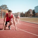 Male athlete in starting position on outdoor track with blurred background.