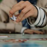 Person rolling dice during a board game, focusing on the hand and dice mid-action.