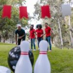 Team of adults playing an outdoor bowling game in a park setting with a focus on fun and teamwork.