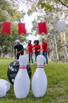 Team of adults playing an outdoor bowling game in a park setting with a focus on fun and teamwork.