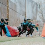 Team of players engaged in an energetic outdoor paintball game, showcasing teamwork and strategy.