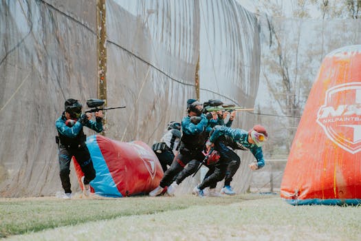 Team of players engaged in an energetic outdoor paintball game, showcasing teamwork and strategy.