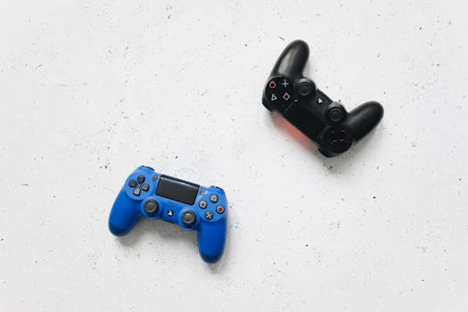 Top view of black and blue PlayStation game controllers on a speckled white surface.
