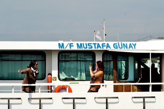 Two women capture memorable moments aboard the M/F Mustafa Günay during a scenic ferry ride.